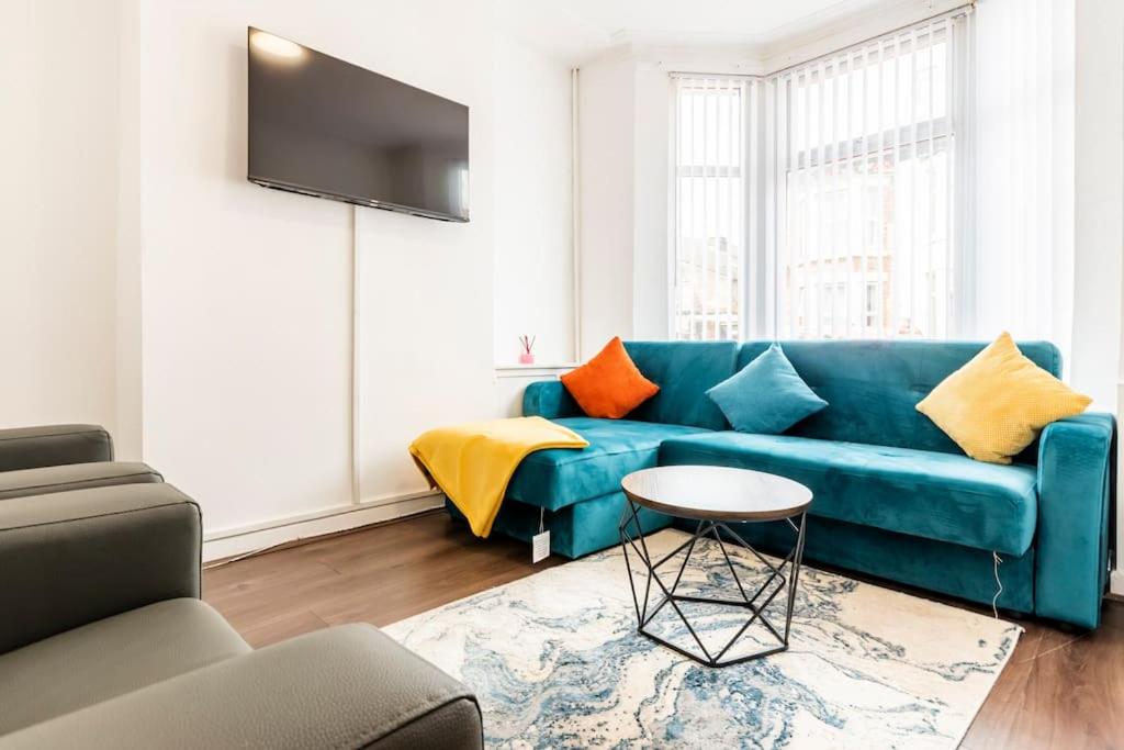 a living room with a blue couch and a table at Home Near Anfield and Everton FC with FREE Parking in Liverpool