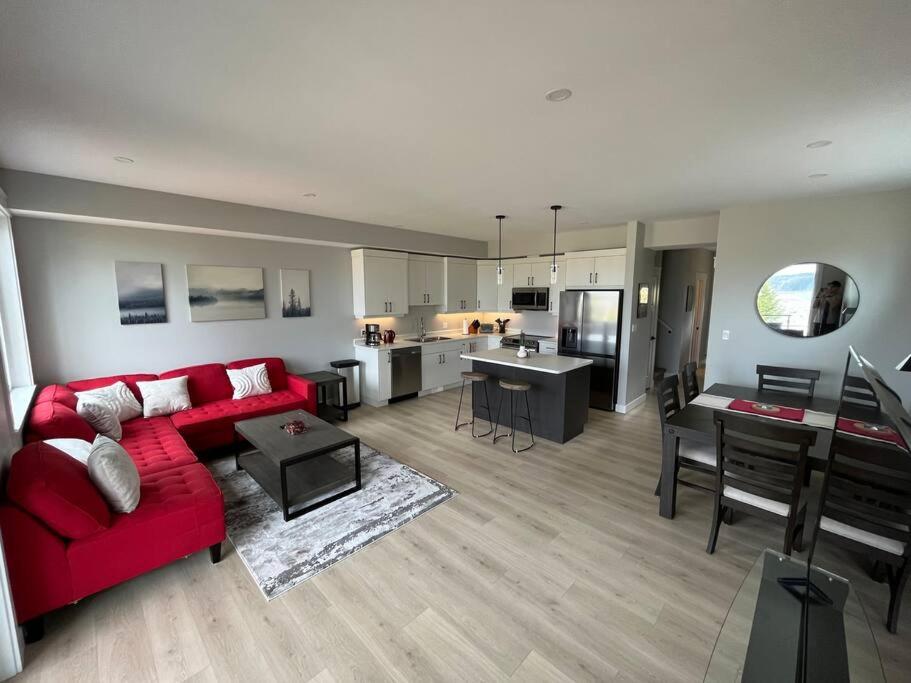 een woonkamer met een rode bank en een keuken bij Ocean View Oasis in Campbell River