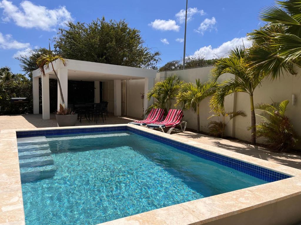 a swimming pool with two chairs and a house at Andira Apartments in Willemstad