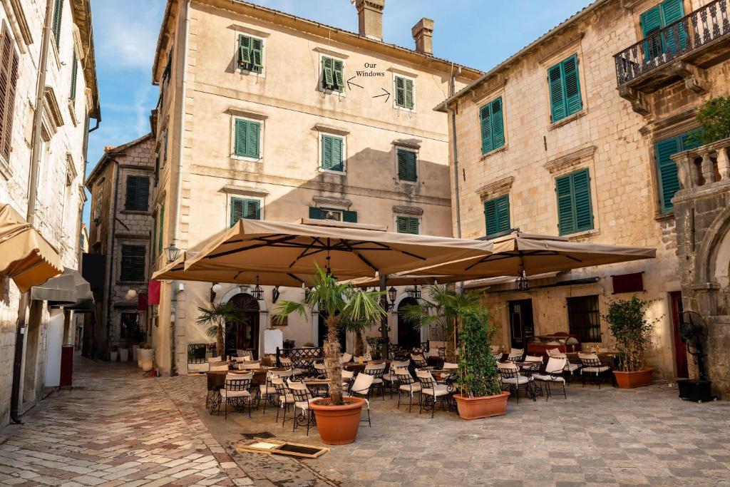 patio ze stołami, krzesłami i parasolami w obiekcie Cozy 2 Bedroom Apartment in Antique Bizanti Palace w Kotorze