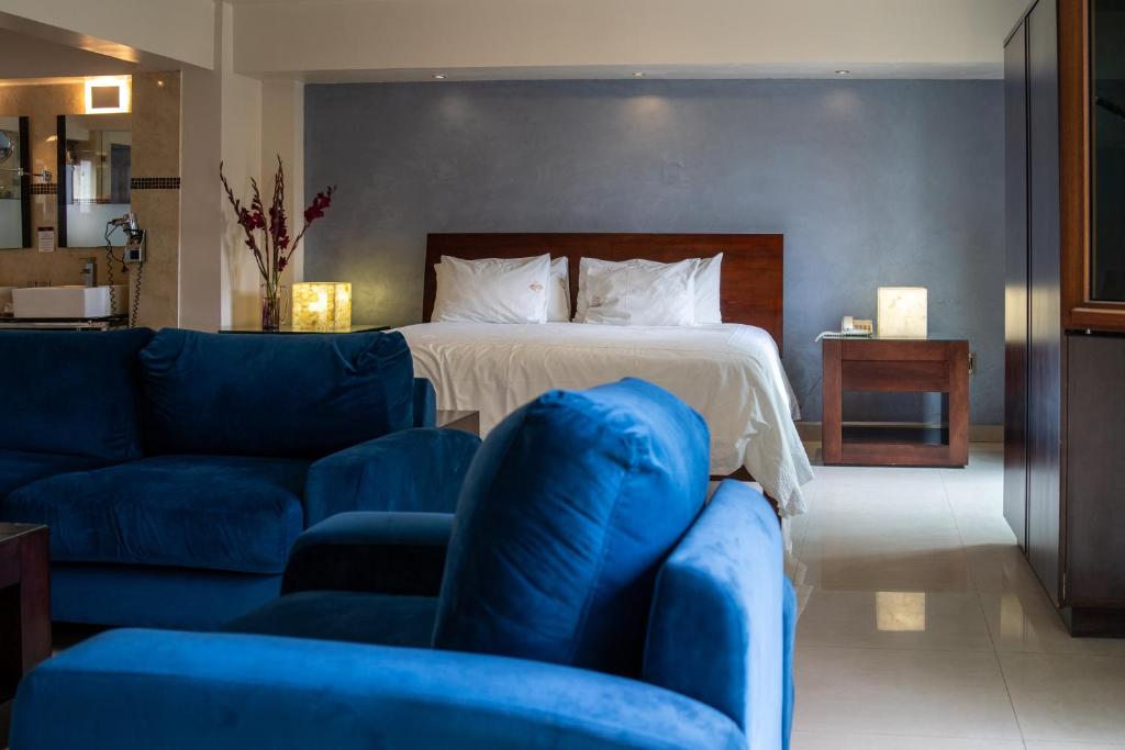 ein Schlafzimmer mit einem Bett und einem blauen Sofa in der Unterkunft Casa de las Flores Hotel in Oaxaca de Juárez