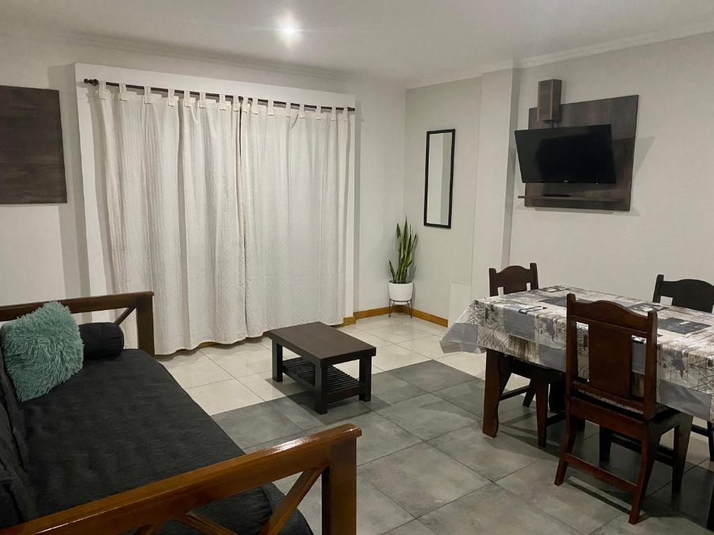 sala de estar con mesa, sofá y TV en Santino Apart en Puerto Iguazú