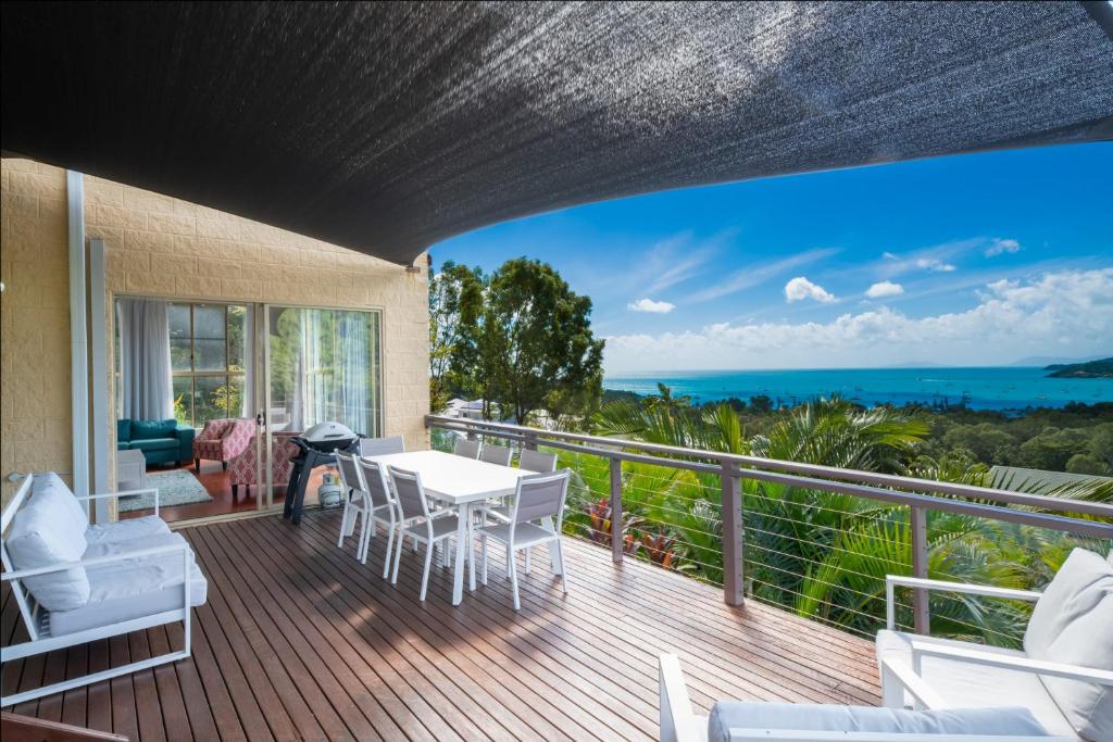 balcón con mesa, sillas y vistas al océano en The Power House - Views & More en Airlie Beach