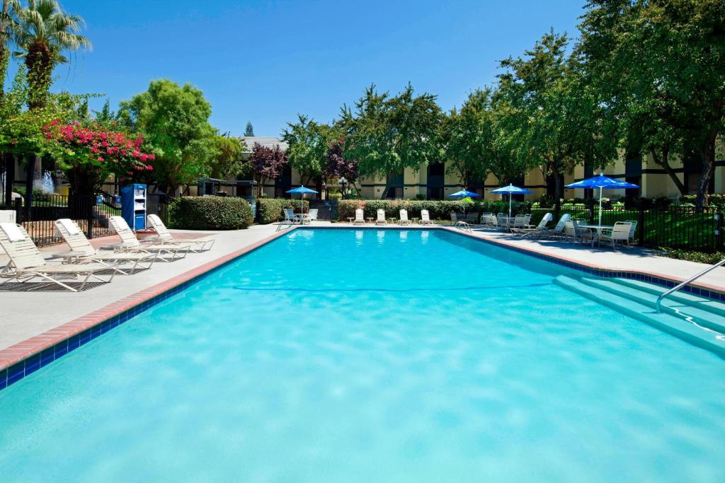 a large swimming pool with chairs and umbrellas at Four Points by Sheraton Bakersfield in Bakersfield