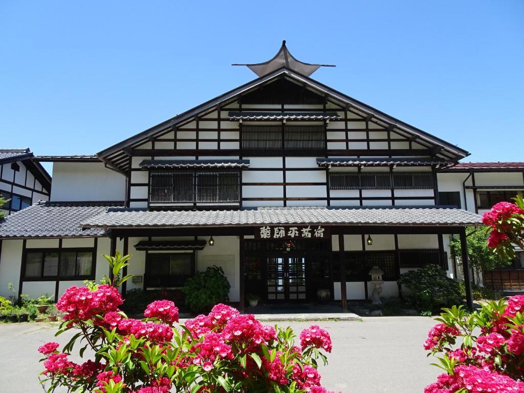 a building with pink flowers in front of it at Yakushidaira Akanejyuku in Matsumoto