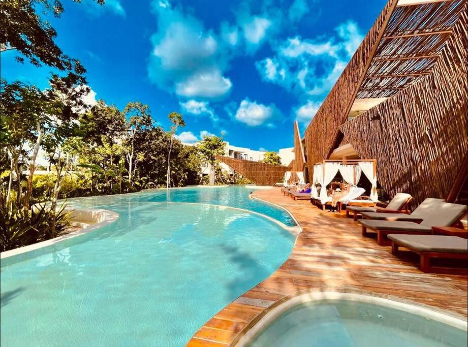 a swimming pool with lounge chairs next to a resort at New Suite Deluxe Tulum Ophelia Community Living in Tulum