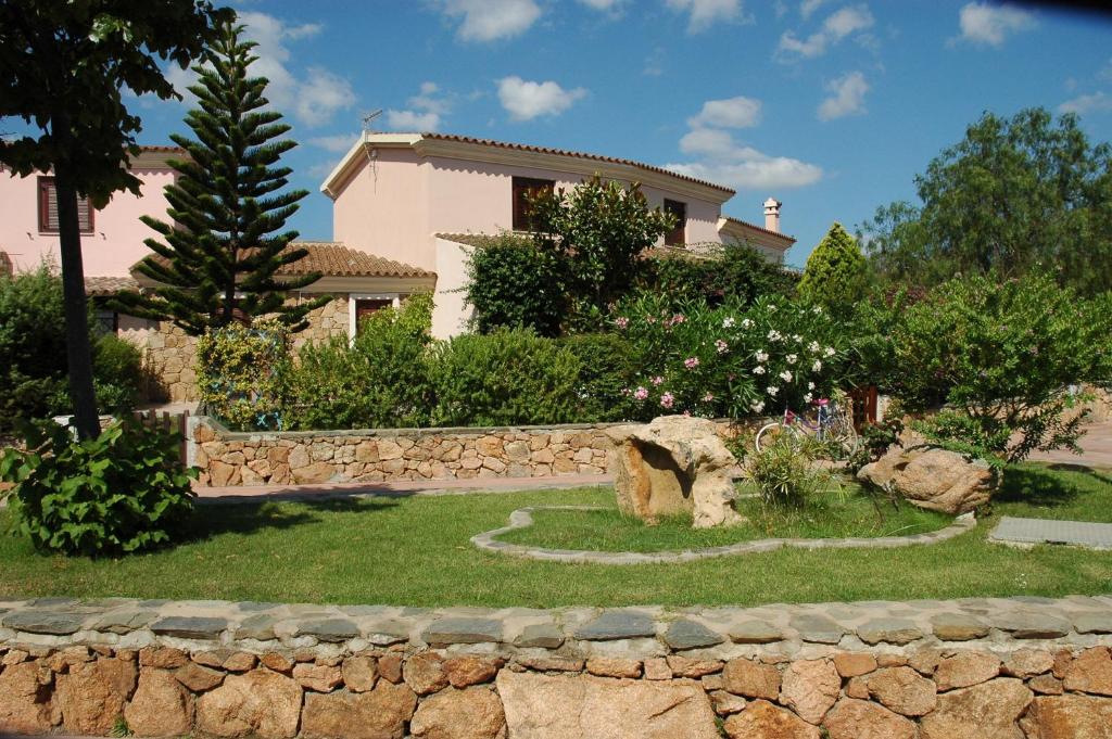 a house with a stone wall in front of a yard at Le Villette di San Teodoro in San Teodoro