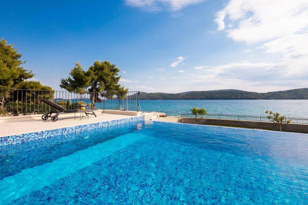 a swimming pool with a view of a body of water at Villa Luxury Maja Zablace in Šibenik