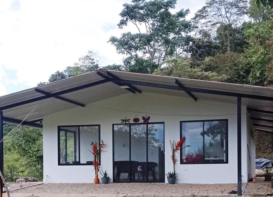 a small white house with glass windows at Casa de campo en La Vega, hermosa vista, con Internet y parqueadero in La Vega