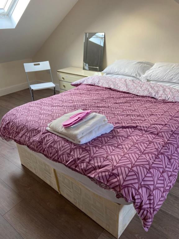 a bed with a pink comforter and a dresser at Glory House in Ilford