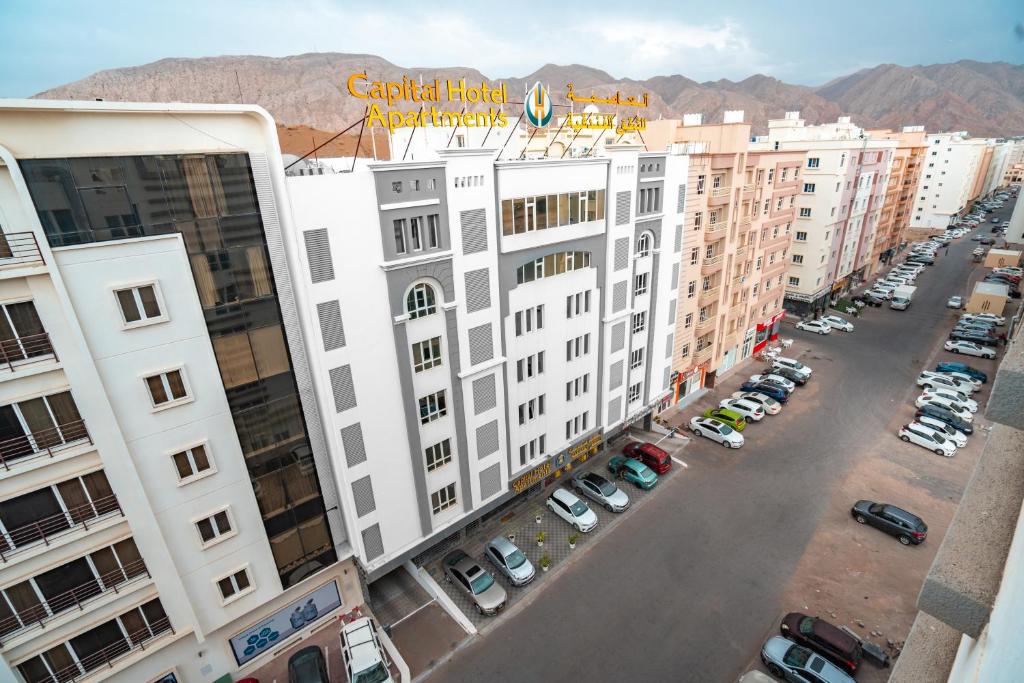 een luchtzicht op een groot wit gebouw met een parkeerplaats bij العاصمة للشقق الفندقية - Capital Hotel Apartments in Muscat