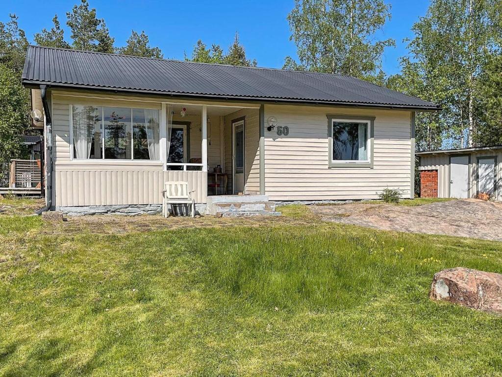 a small white house with a porch on a yard at Holiday home Kristinehamn VI in Kristinehamn