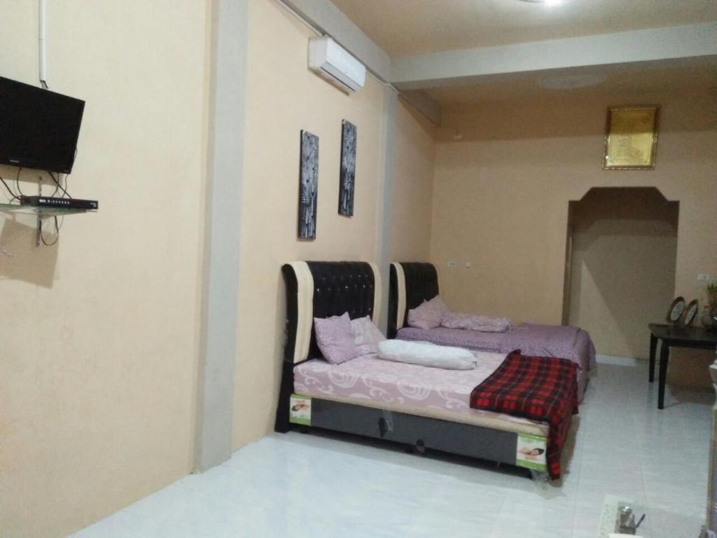IboihにあるFURQAN GUEST HOUSE Familyのベッドとテレビのある寝室