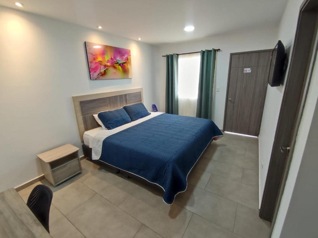 a bedroom with a bed with a blue comforter at Hotel Villa Bosco in Palmira