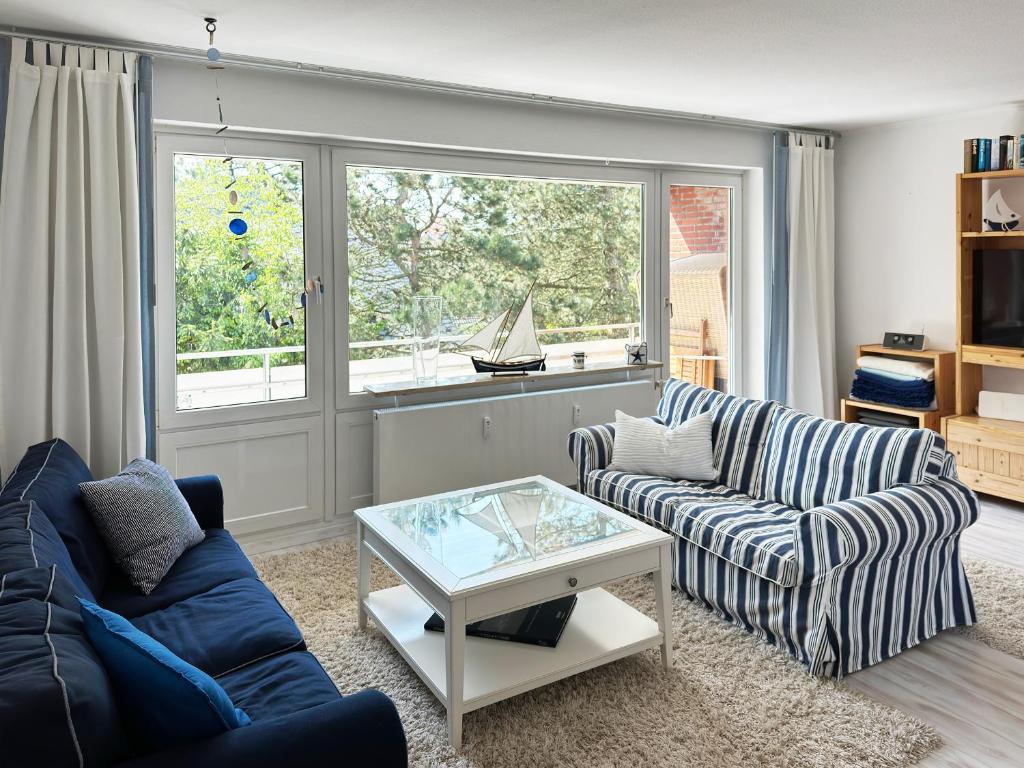 a living room with two couches and a glass table at Ferienwohnung Möwenweg 9 Whg 28 in Wittdün