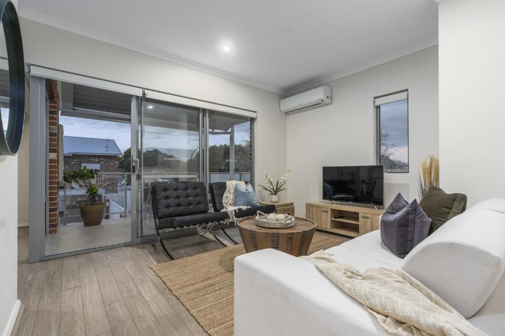 uma sala de estar com um sofá branco e uma televisão em Modernista Getaway Your Airport Retreat em Perth
