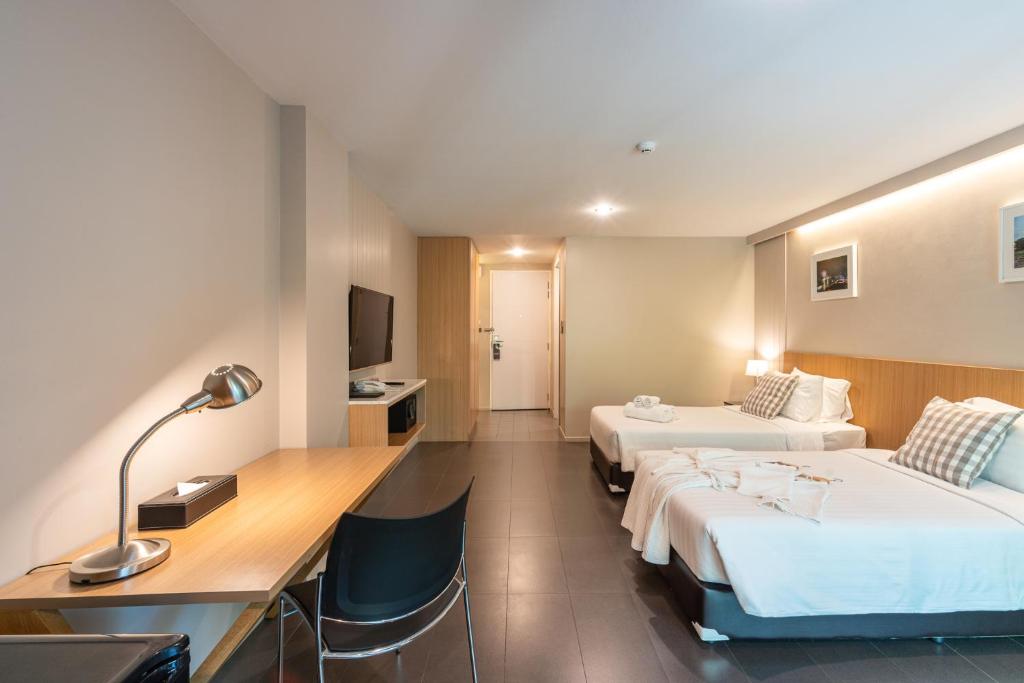 A twin room with a proper writing desk, chair and wall-mounted television.