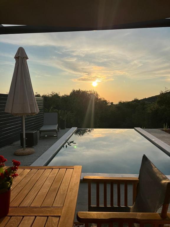 a view of a swimming pool with the sun setting at Elaionas Estate Perdika in Perdika