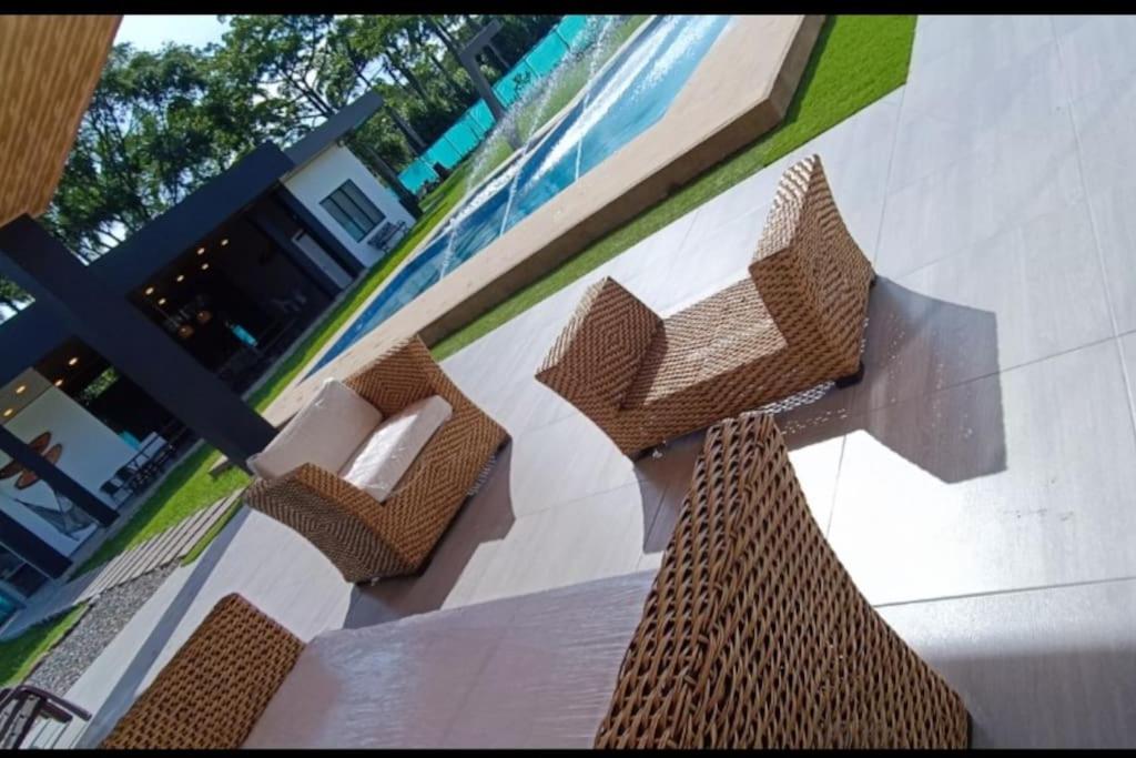 a patio with two wicker chairs and a pool at Quinta La Bonita Restrepo Meta in Restrepo