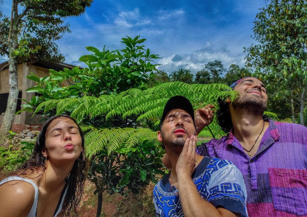 a group of three people standing next to a plant at Farmstay Manangel in Sindanglaka