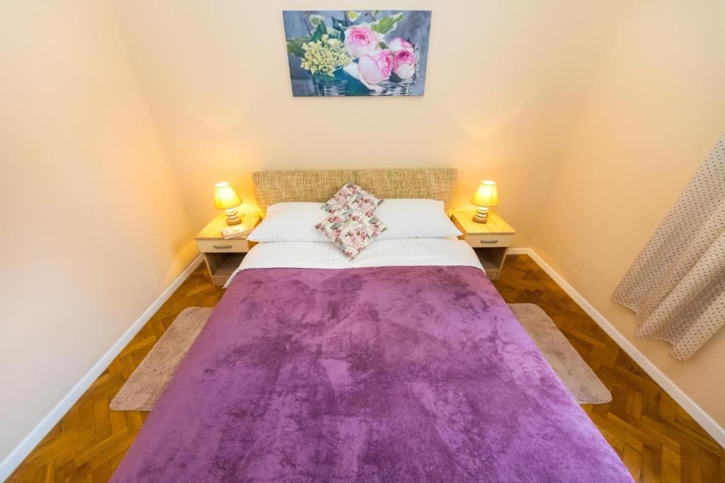 a bedroom with a purple blanket on a bed at Apartment Colona in Zadar