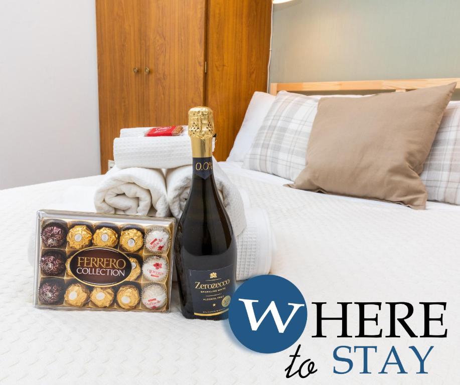een fles champagne en een doos donuts op een bed bij WhereToStay Apartment River Side in Aberdeen