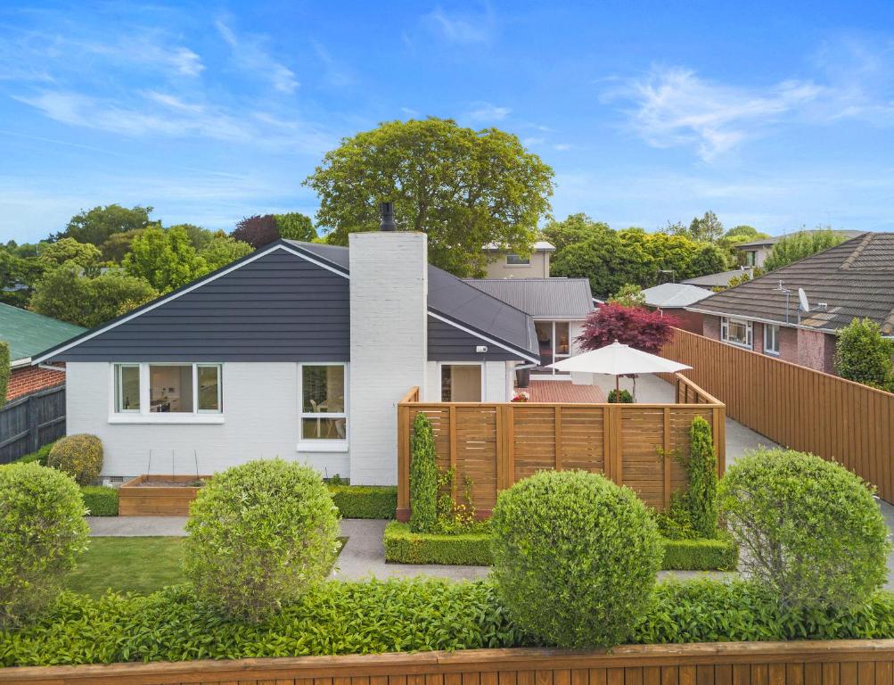uma casa branca com uma cerca e arbustos em Family-Friendly, Airport 6 mins, Spacious with Garden em Christchurch