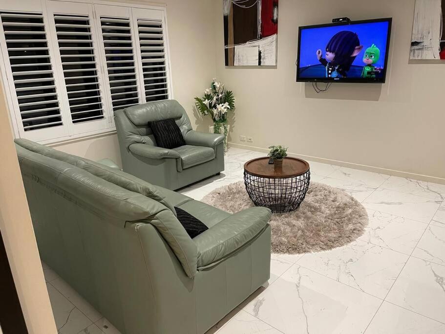 a living room with two chairs and a tv at Refurbished Family Home in Glen Waverley