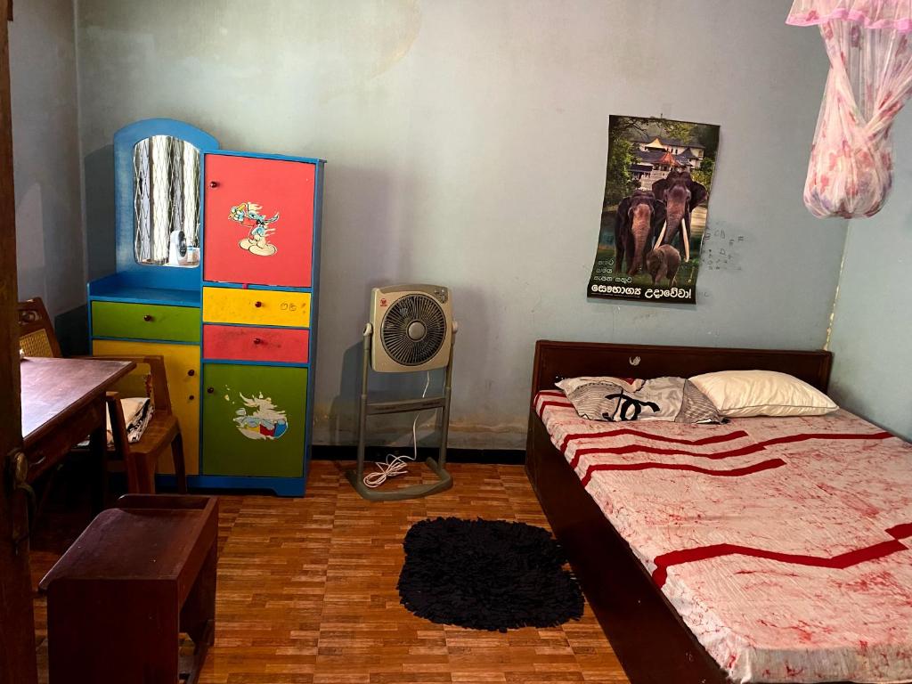 een slaapkamer met een bed, een bureau en een ventilator bij OM Homestay in Bentota
