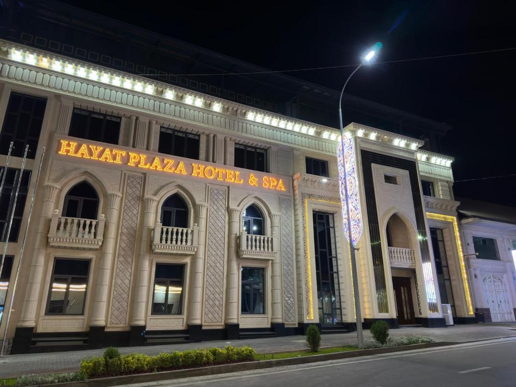 un grand bâtiment avec un panneau éclairé dans l'établissement HAYAT PLAZA HOTEL & Spa, à Samarcande