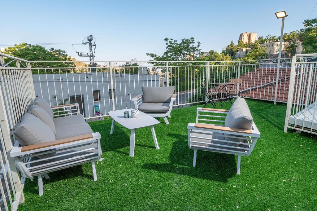 eine Terrasse mit 3 Stühlen und einem Tisch auf dem Rasen in der Unterkunft Moses Luxury Vacation Homes הבית בכ"ה in Safed