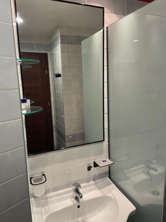 bagno con lavandino e grande specchio di Port Balchik apartment a Balchik