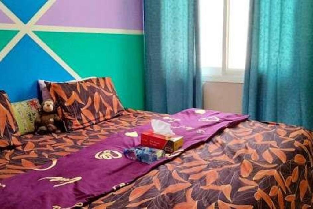 een bed met een paars dekbed met een doos erop bij Sharaf DG Metro Unisex PARTITION Private room -40-02 in Dubai