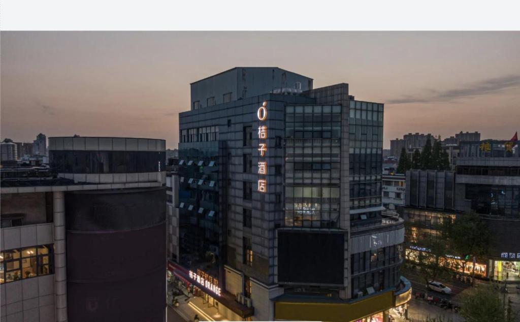 um edifício alto com um cartaz numa cidade em Orange Hotel - Taicang Nanyang Plaza em Taicang