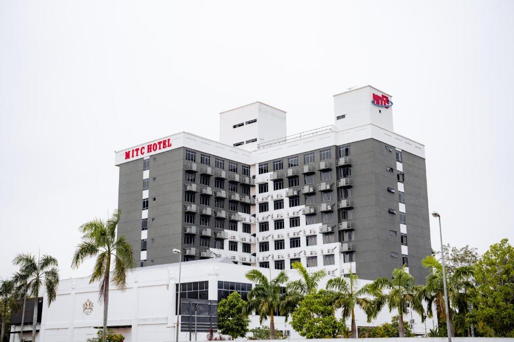 a hotel building with palm trees in front of it at MITC Hotel in Melaka