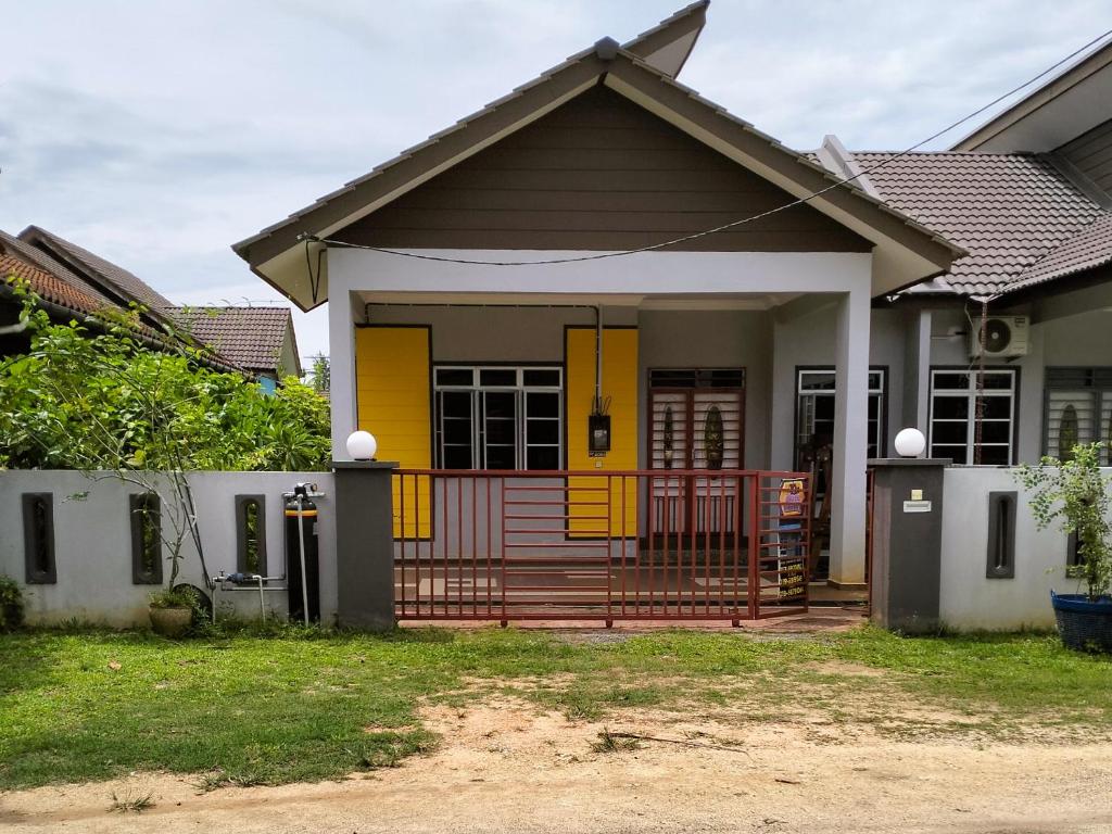 uma pequena casa com uma porta amarela em dRose Homestay em Kuala Terengganu