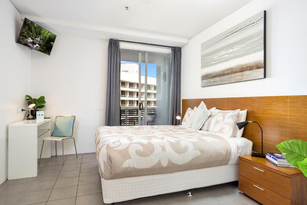 a bedroom with a bed and a desk and a window at Marina View Queen Bed Studio Apartment Pool & Gym in Cairns
