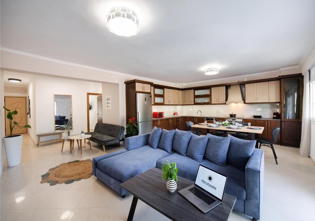 a living room with a blue couch and a kitchen at Peratzada apartments in Vasiliki