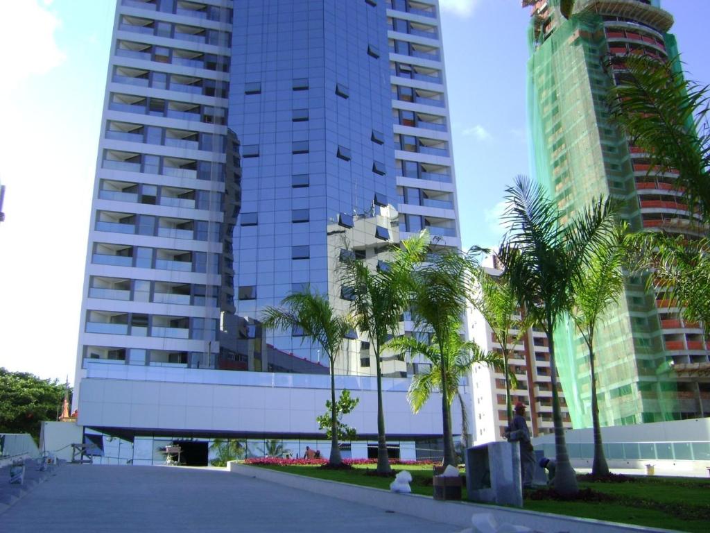 un edificio con palmeras frente a edificios altos en Boa Viagem 420 Apart Hotel, en Recife