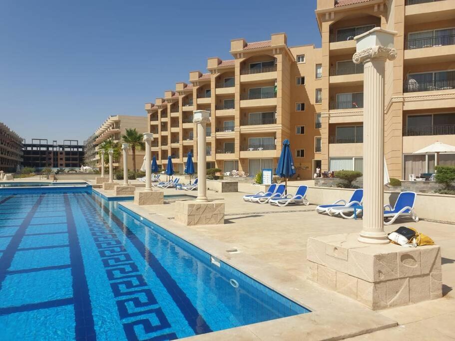 Amazing 2 bedroom Selena Bay Hurghada في الغردقة: مسبح وكراسي صالة ومبنى