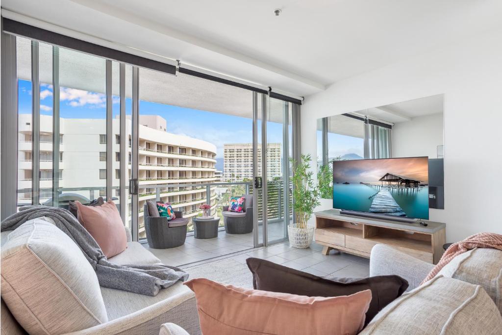 een woonkamer met een bank en een tv bij Luxury 1BR Apartment @ Harbour Lights Cairns in Cairns