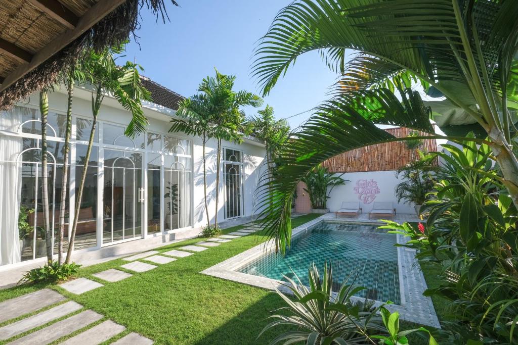 an exterior view of a house with a swimming pool and palm trees at No Rush Villas in Canggu