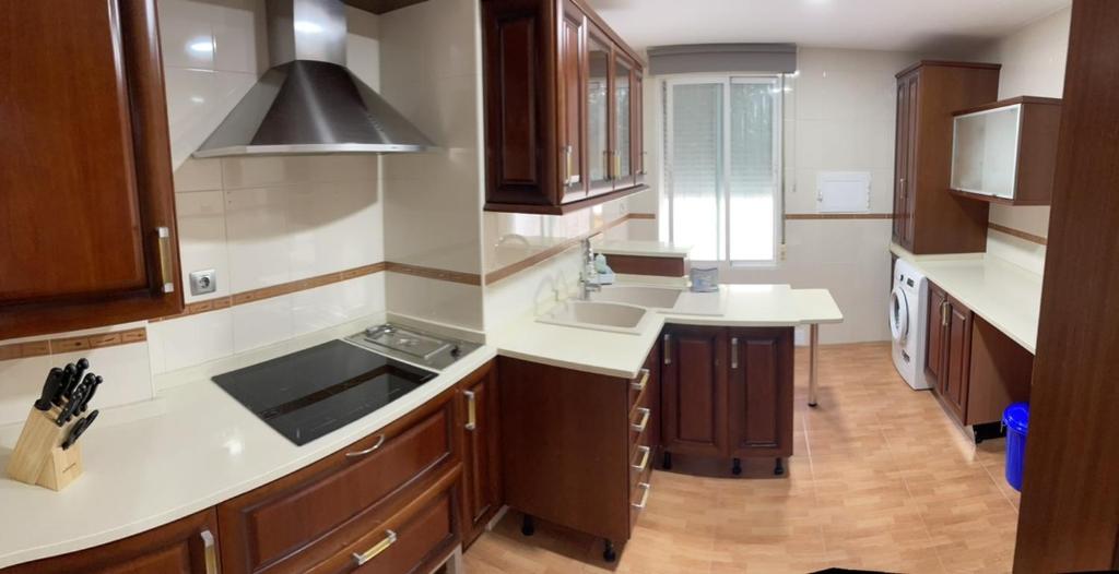 a large kitchen with wooden cabinets and white counter tops at Vivienda Fines Turísticos La Victoria in Jaén