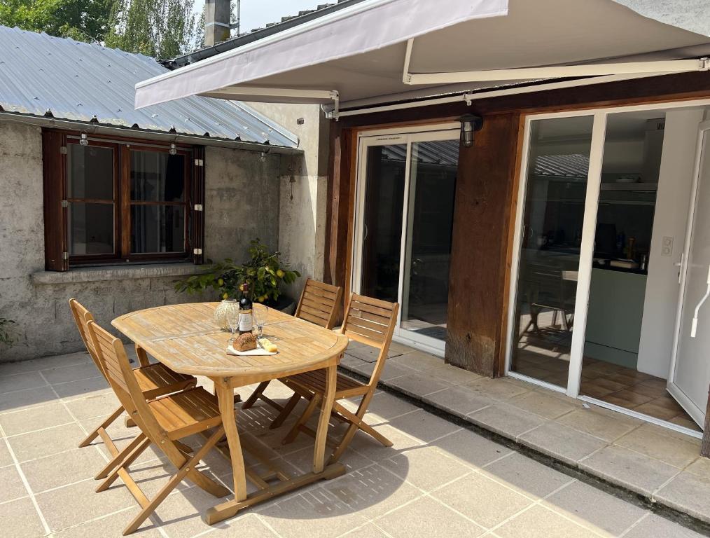 einen Holztisch und Stühle auf einer Terrasse in der Unterkunft Luxurious Garden Cottage in Argelès-Gazost