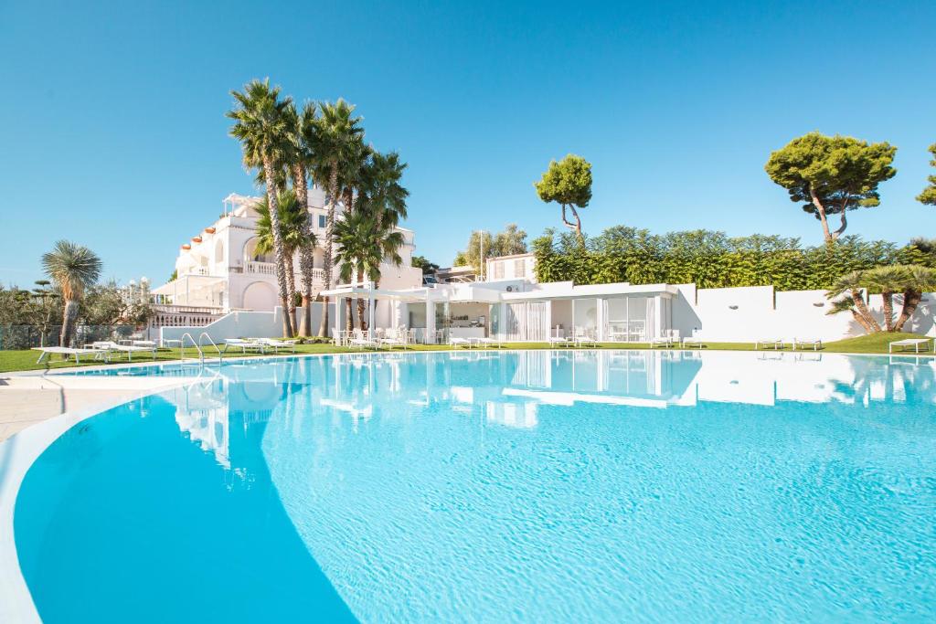 a large swimming pool with palm trees and a house at Villa Coppitella, rooms & apartments in Vieste