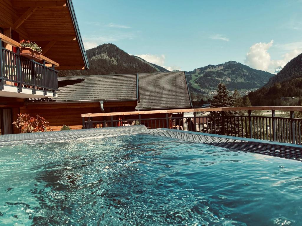 a swimming pool in front of a house with mountains at Terra-Beka Lodge in La Chapelle-dʼAbondance