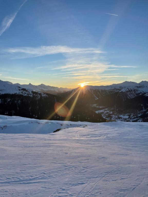 a view of the sun setting over a snow covered mountain at 2.5 Zimmer Wohnung Davos Platz in Bolgen