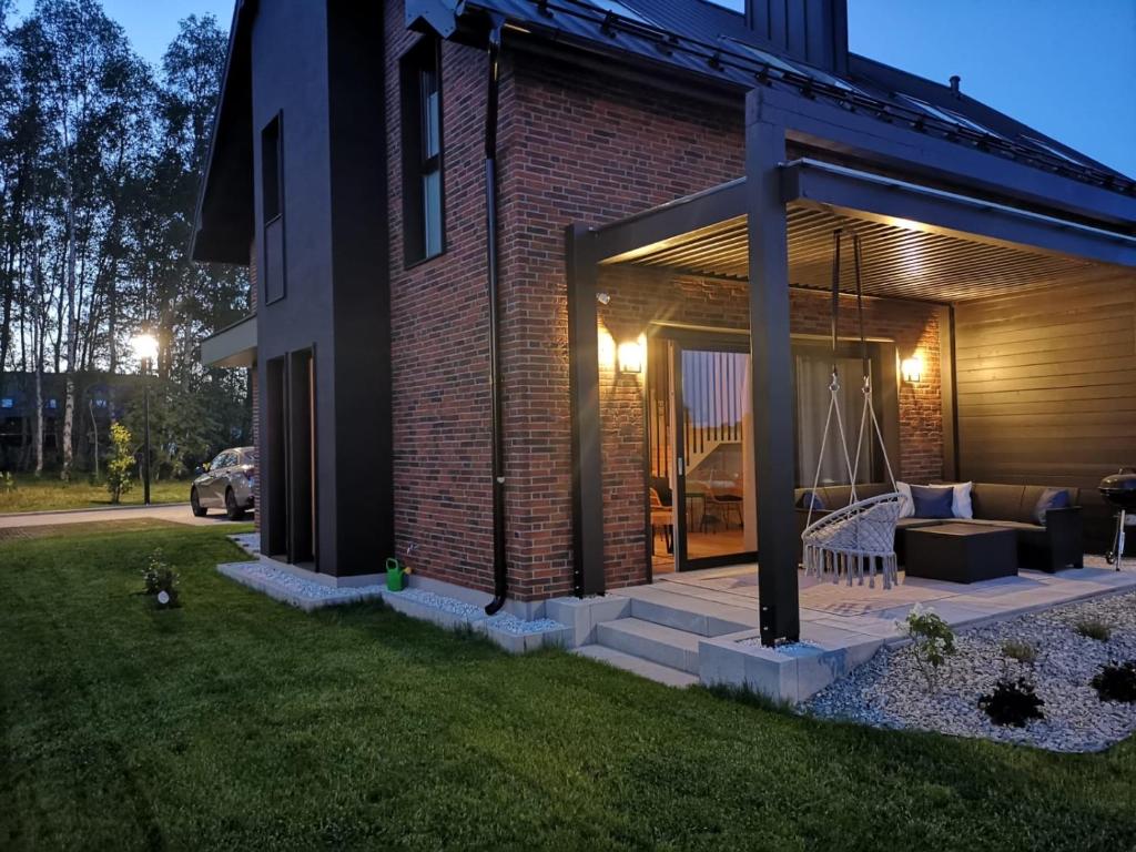 a brick house with a porch with a swing at Norda Loft in Dębki
