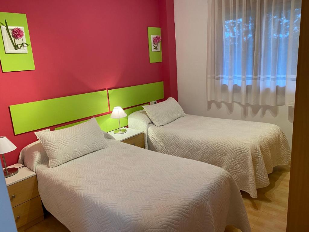 2 camas en una habitación con paredes rojas y verdes en Apartamentos Alcañiz, Marisol en Alcañiz