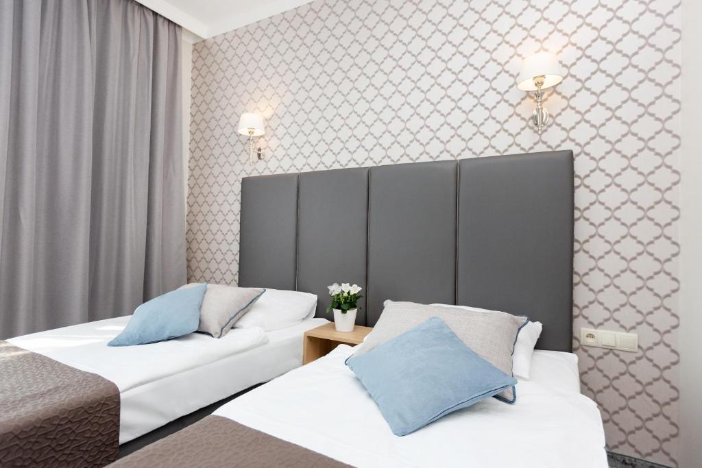 um quarto de hotel com duas camas e um sofá em Villa Grand Solis em Świnoujście